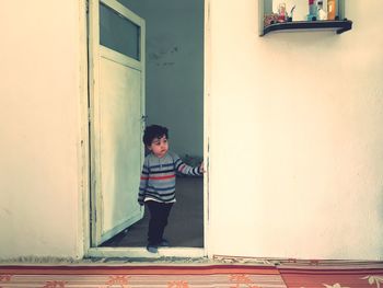 Boy standing by door of building