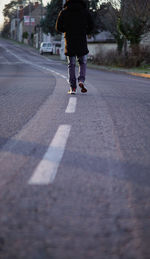 Rear view of man walking on road