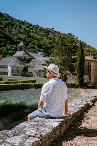 Man wearing hat against trees and plants against sky