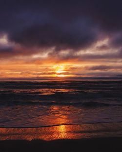 Scenic view of sea against dramatic sky during sunset