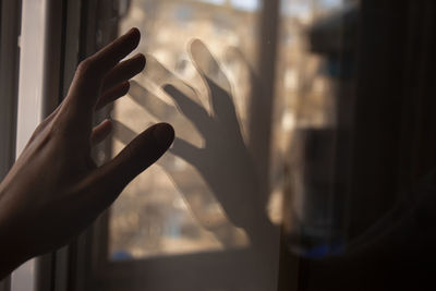 Cropped hand of person touching glass window