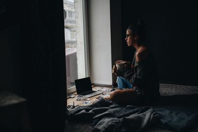 Woman drinking coffee while sitting on floor at home