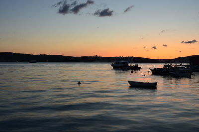 Silhouette boats in sea against sky during sunset