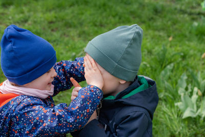 Girl covered the boy's eyes with her hands. children playing outside on a spring day. 