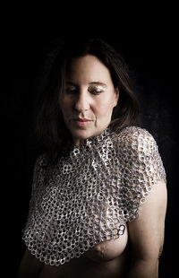 Portrait of young woman standing against black background