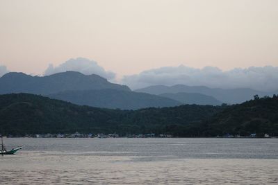 Scenic view of sea and mountains against sky during sunset