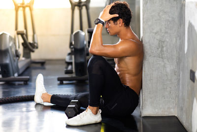 Side view of man sitting in gym