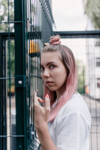 Portrait of woman standing against railing