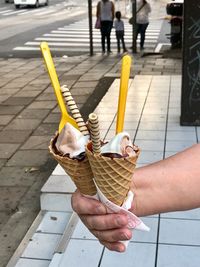 Woman holding ice cream on footpath