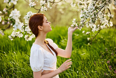 Side view of young woman holding flowers