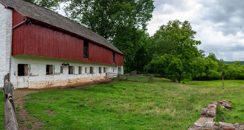 House on field by trees against sky