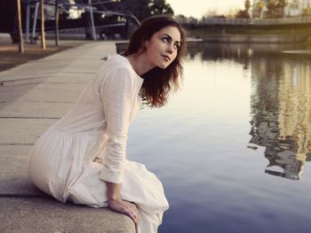 Portrait of young woman sitting by lake