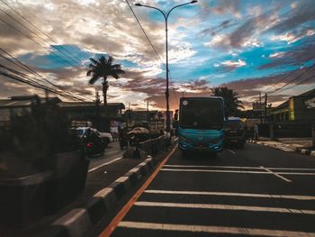 Vehicles on road against sky in city