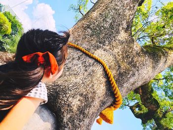 Portrait of woman by tree trunk against plants