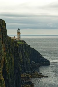 Lighthouse by sea against sky