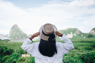 Rear view of woman standing on mountain against sky