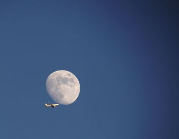 Low angle view of moon against clear blue sky