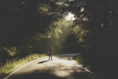 Man walking on road amidst trees in forest