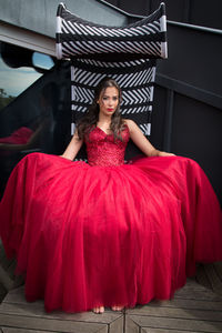 Portrait of young woman in red dress sitting outdoors