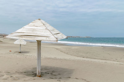 Beach hut on sand against sky