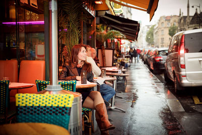 Attractive woman in a black jacket sits in the street cafe
