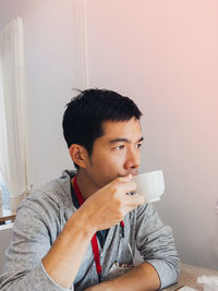 Portrait of young man drinking beer at home