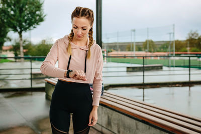 Young woman looking away while standing on railing