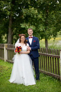 Portrait of smiling young couple standing on grassy field