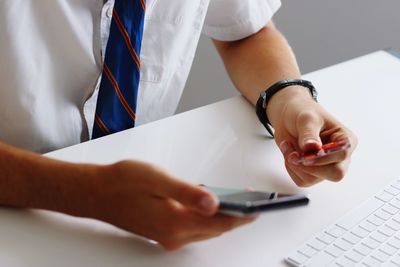 Midsection of man using mobile phone on table