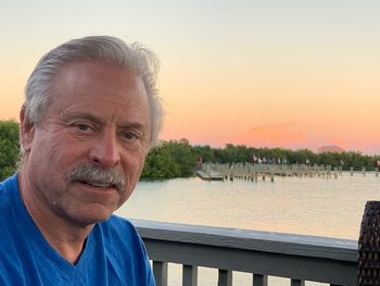 Portrait of man by lake against sky during sunset