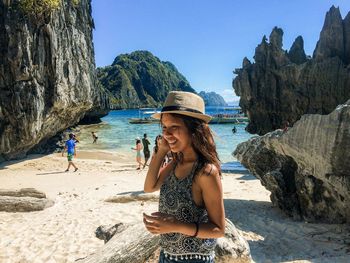 Smiling woman wearing hat standing on beach