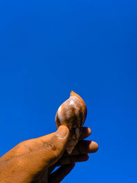 Person holding ice cream against blue sky