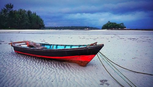 Boat moored on shore against sky