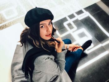 High angle portrait of young woman applying lipstick