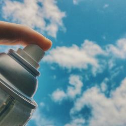 Low angle view of cropped hand against sky