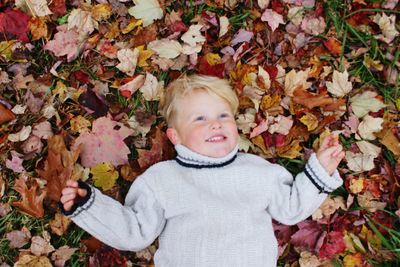 Portrait of smiling boy on leaves during autumn