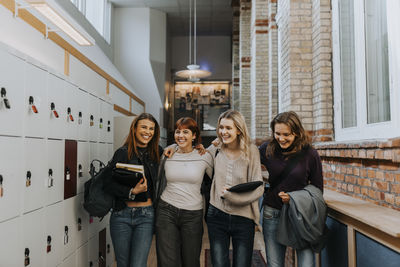 Happy female students walking in school corridor