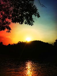 Silhouette trees by lake against sky during sunset