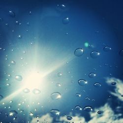 Low angle view of water drops on blue sky