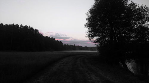 Road amidst trees on field against sky