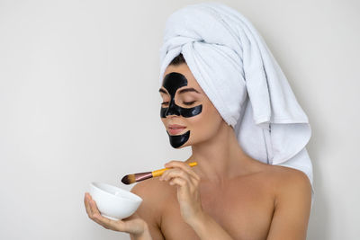 Young and beautiful woman with black peel-off mask on her face