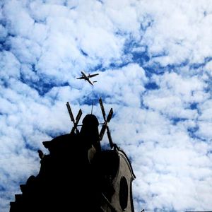 Low angle view of silhouette airplane flying against sky