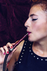 Close-up of young woman smoking hookah