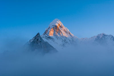 Scenic view of snowcapped mountains against clear blue sky