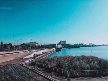 Bridge over river in city against clear blue sky
