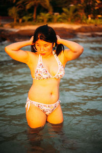 Portrait of young woman wearing sunglasses while standing at beach