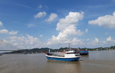 View of boats in river against cloudy sky