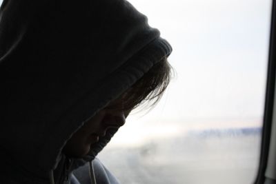 Close-up of person wearing hooded shirt by car window