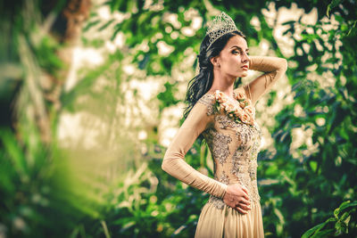 Portrait of young woman standing against tree