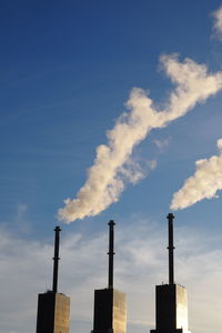 Low angle view of smoke stack against blue sky